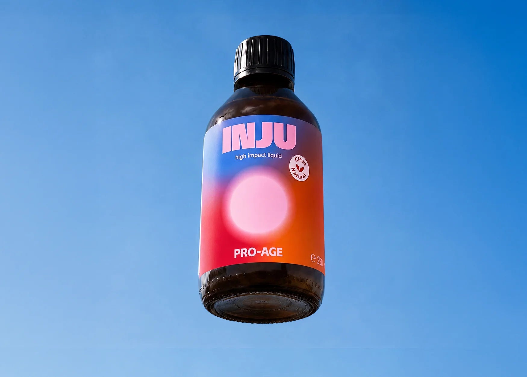 INJU PRO-AGE-Braunglasflasche vor blauem Himmel. Das blau-rote Etikett zeigt das Logo und einen sanft rosa leuchtenden Kreis.