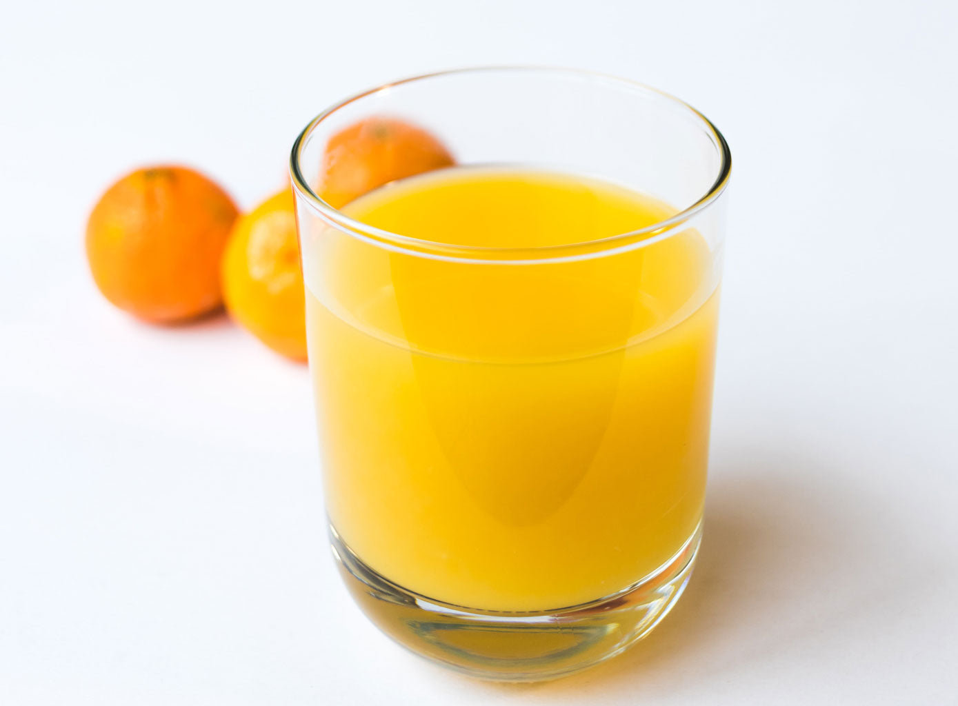 Ein Glas Orangensaft und drei Orangen