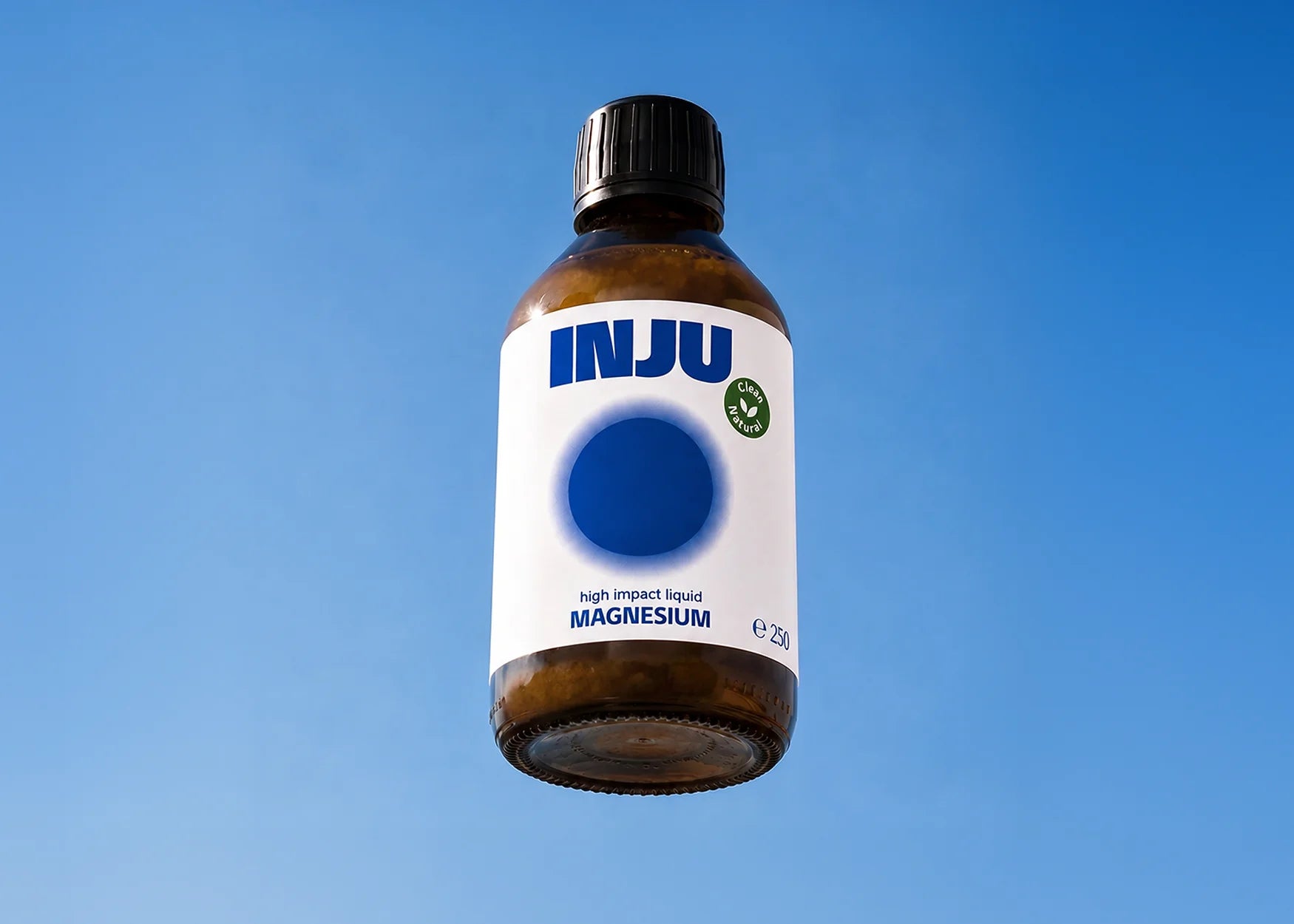INJU MAGNESIUM Glasflasche vor blauem Himmel. Das weiße Etikett zeigt das Logo und einen leuchtend blaufarbenen Kreis.